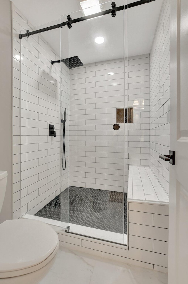 bathroom with a shower with shower door and toilet