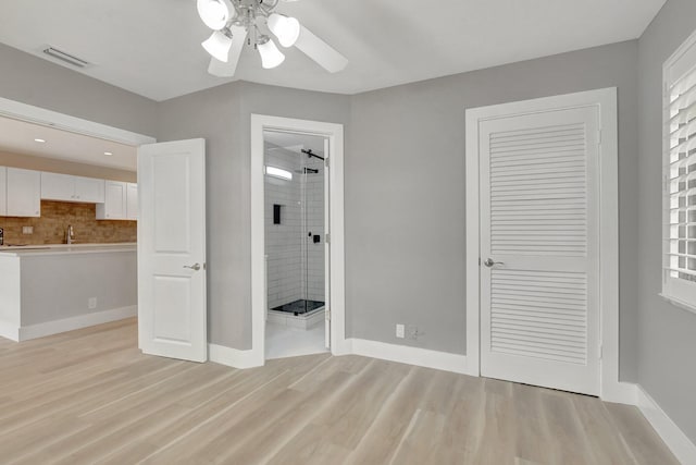 unfurnished bedroom featuring a closet, light hardwood / wood-style floors, connected bathroom, ceiling fan, and sink