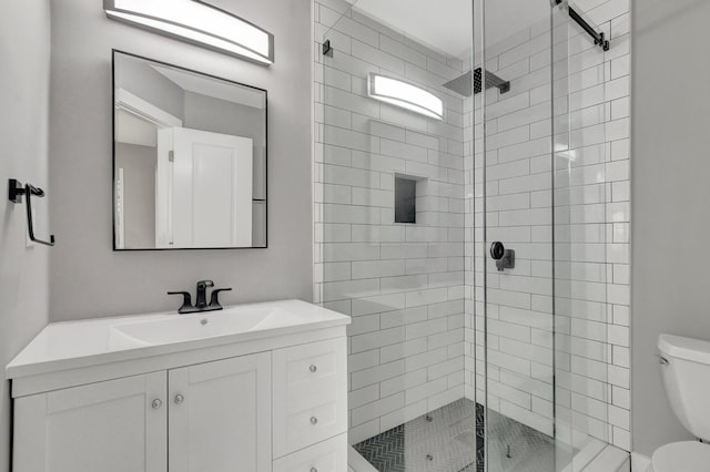 bathroom featuring toilet, a shower with door, and vanity