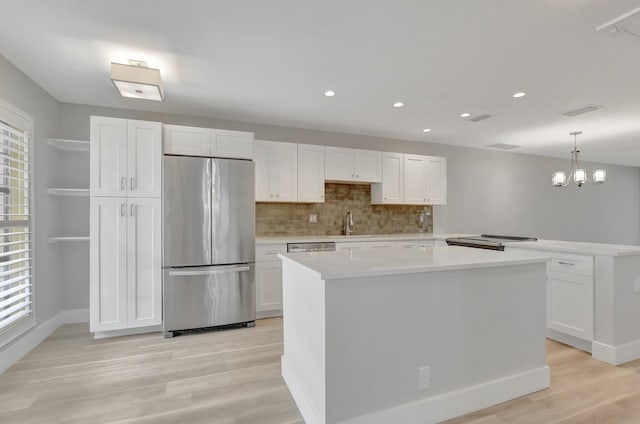 kitchen featuring a kitchen island, stainless steel appliances, decorative light fixtures, and white cabinetry