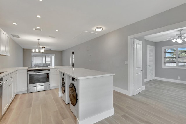 kitchen with stainless steel appliances, white cabinets, decorative light fixtures, washer and clothes dryer, and a kitchen island