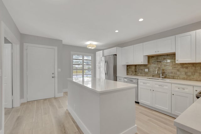 kitchen with a kitchen island, white cabinets, appliances with stainless steel finishes, and backsplash