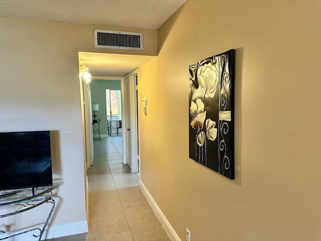 hallway with light tile patterned flooring and a textured ceiling