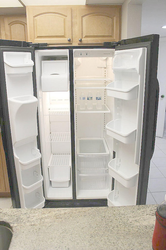 interior details with white refrigerator with ice dispenser and light brown cabinetry