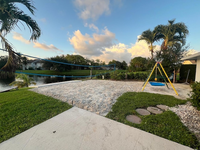 view of home's community with a water view, a yard, and volleyball court