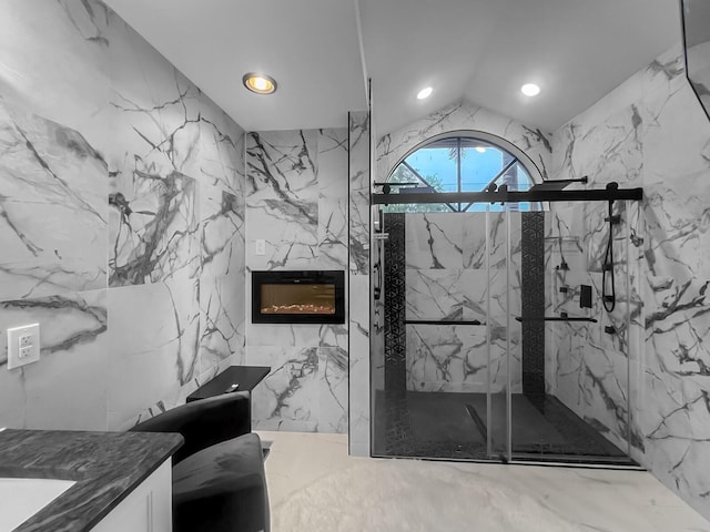 bathroom featuring vanity, a high end fireplace, a shower with shower door, and lofted ceiling