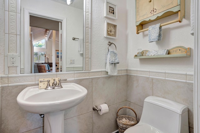 bathroom featuring tile walls and toilet