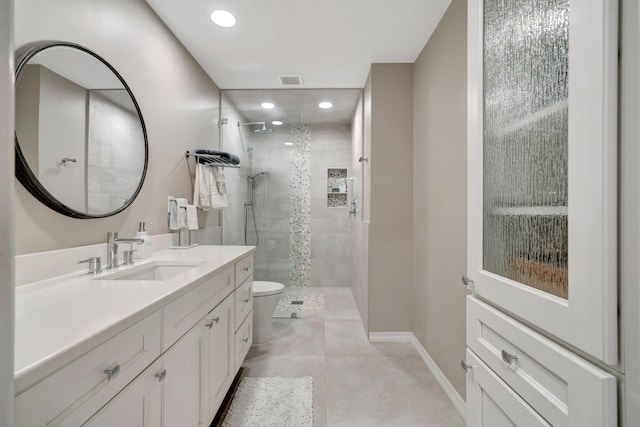 bathroom featuring vanity, tiled shower, tile patterned floors, and toilet