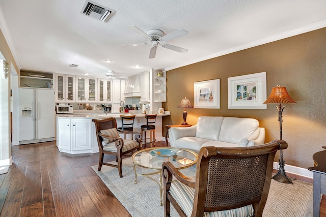 living room with ornamental molding, dark wood-type flooring, a textured ceiling, and ceiling fan