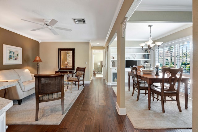 dining space with crown molding, dark hardwood / wood-style flooring, built in shelves, and ceiling fan with notable chandelier