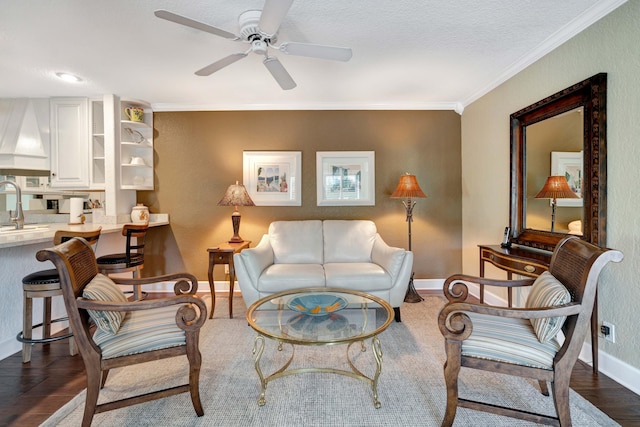 living room featuring dark wood-type flooring, ceiling fan, ornamental molding, and sink