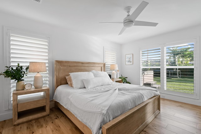 bedroom with ceiling fan, light wood-type flooring, and multiple windows