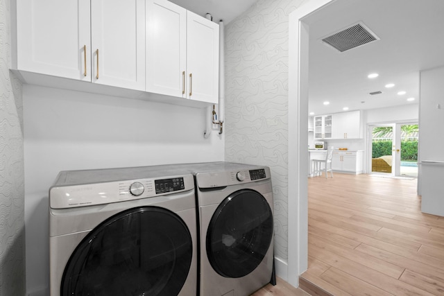 washroom with washer and clothes dryer, light hardwood / wood-style floors, and cabinets