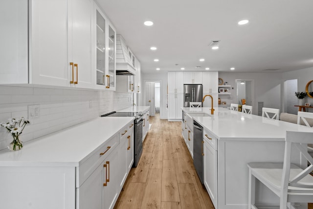 kitchen featuring white cabinets, appliances with stainless steel finishes, a large island, and a kitchen breakfast bar