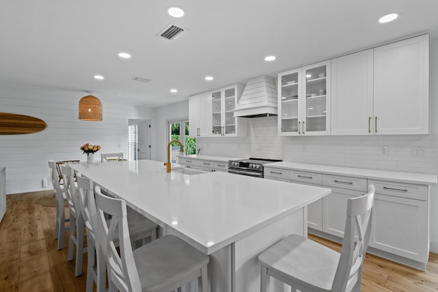 kitchen featuring electric stove, custom range hood, a large island, white cabinets, and sink