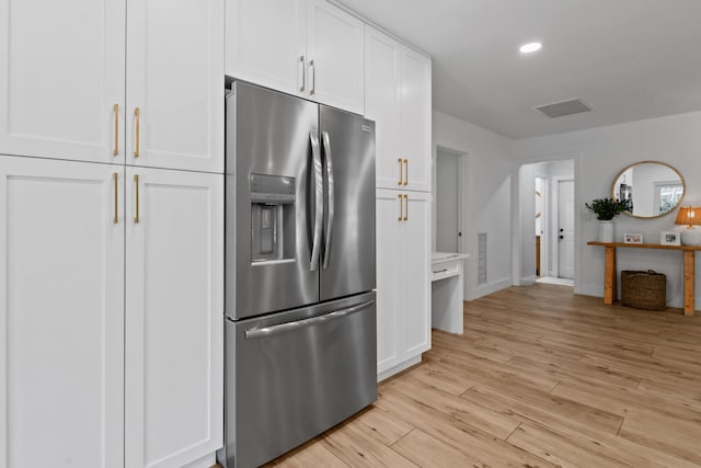 kitchen with light hardwood / wood-style flooring, stainless steel refrigerator with ice dispenser, and white cabinetry