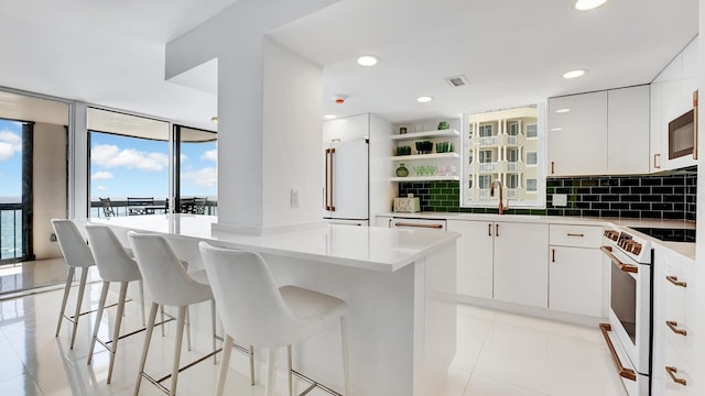 kitchen with a center island, white appliances, expansive windows, sink, and white cabinetry