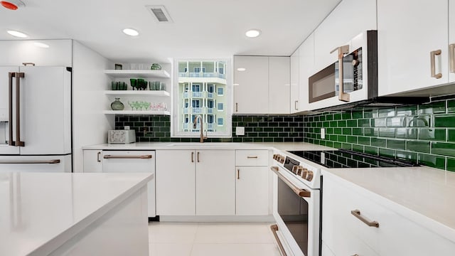 kitchen with tasteful backsplash, white appliances, sink, light tile patterned floors, and white cabinets