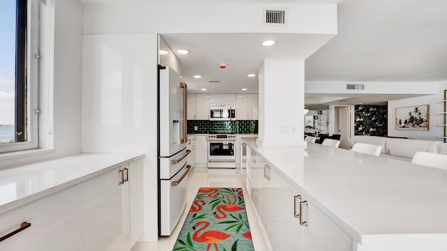 kitchen featuring white appliances, white cabinetry, a breakfast bar area, and light tile patterned floors