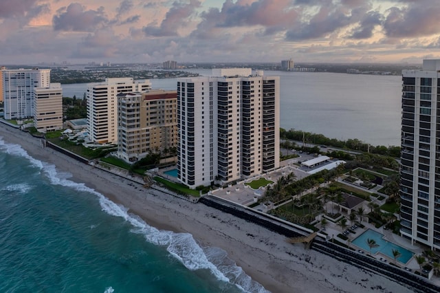 aerial view at dusk with a water view and a beach view