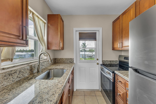 kitchen featuring light stone countertops, plenty of natural light, stainless steel appliances, and sink