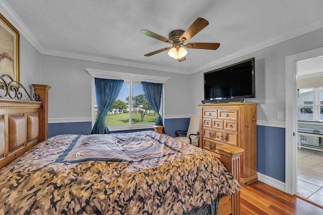 bedroom with light hardwood / wood-style flooring, ceiling fan, and ornamental molding