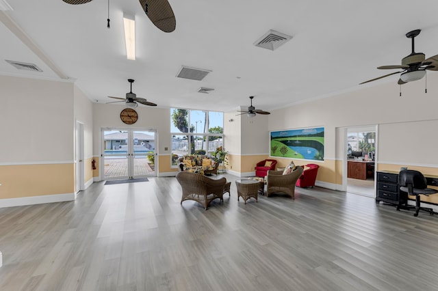 living room featuring french doors, light wood-type flooring, ceiling fan, and crown molding