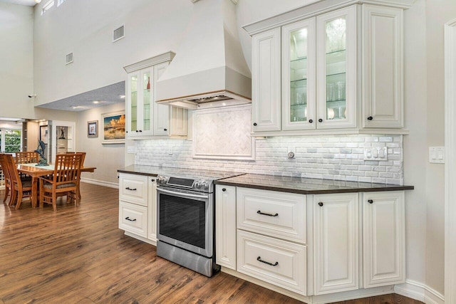 kitchen with dark wood finished floors, dark countertops, stainless steel range with electric stovetop, and premium range hood