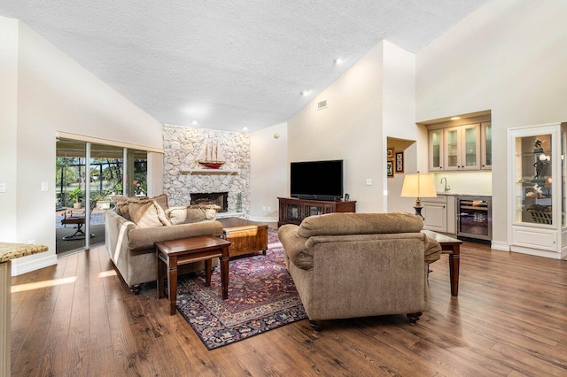 living room with visible vents, a fireplace, dark wood-style flooring, indoor wet bar, and wine cooler