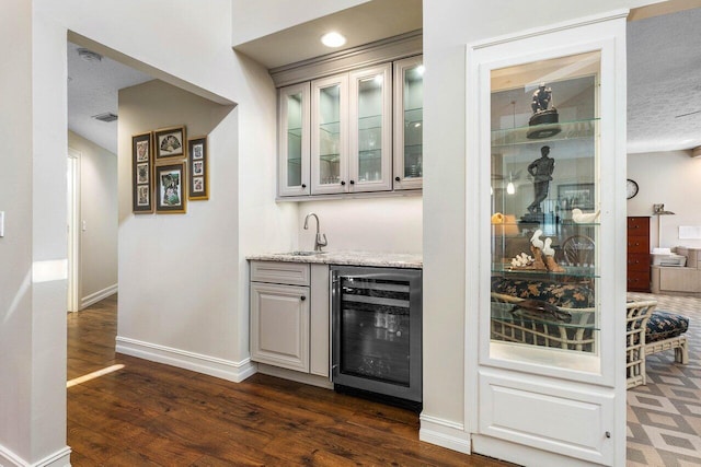 bar featuring visible vents, beverage cooler, a sink, baseboards, and wet bar