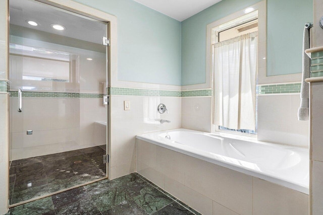 bathroom featuring tile walls, plenty of natural light, a bath, and a stall shower