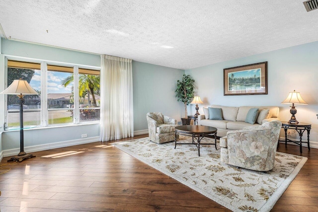 living area featuring visible vents, baseboards, a textured ceiling, and wood finished floors