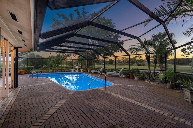 outdoor pool featuring glass enclosure and a patio