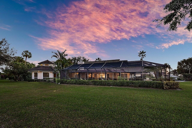 rear view of house with a lanai and a lawn