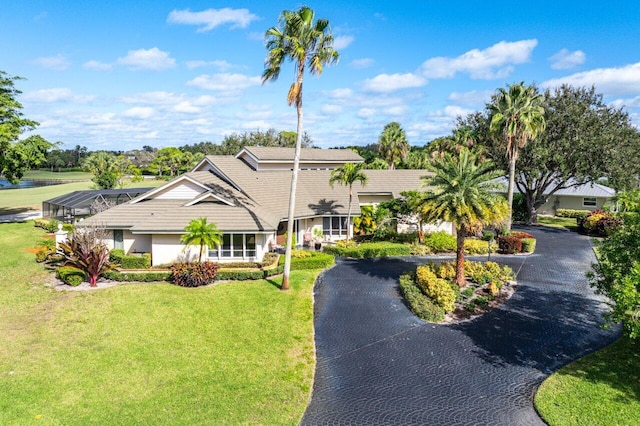 view of front of home with glass enclosure, aphalt driveway, and a front lawn