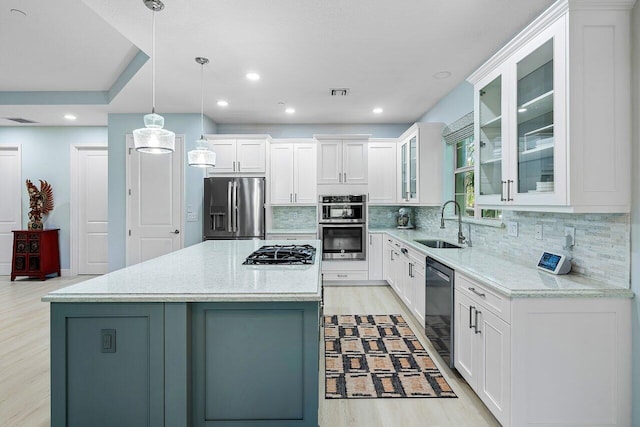 kitchen with light stone counters, a kitchen island, hanging light fixtures, and appliances with stainless steel finishes