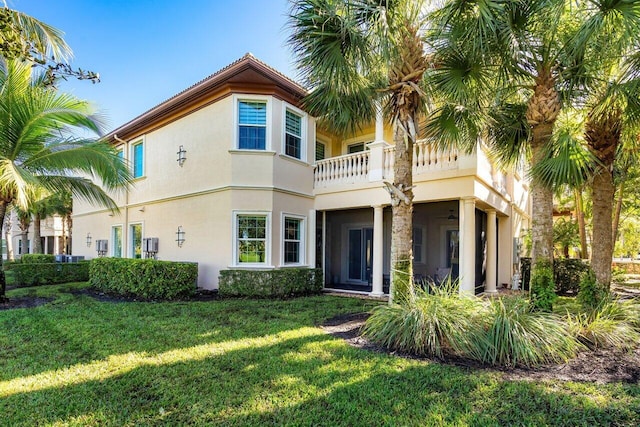 rear view of property featuring a lawn and a balcony