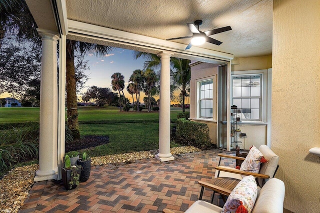 patio terrace at dusk with a yard and ceiling fan