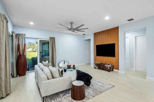 living room with a textured ceiling, light hardwood / wood-style floors, and ceiling fan