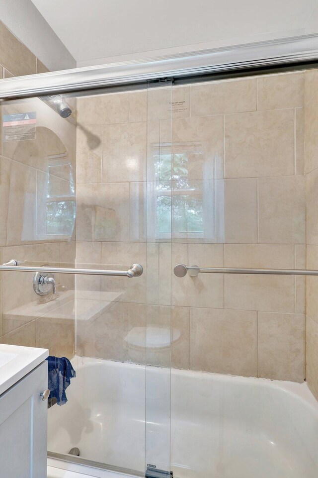 bathroom featuring shower / bath combination with glass door and vanity