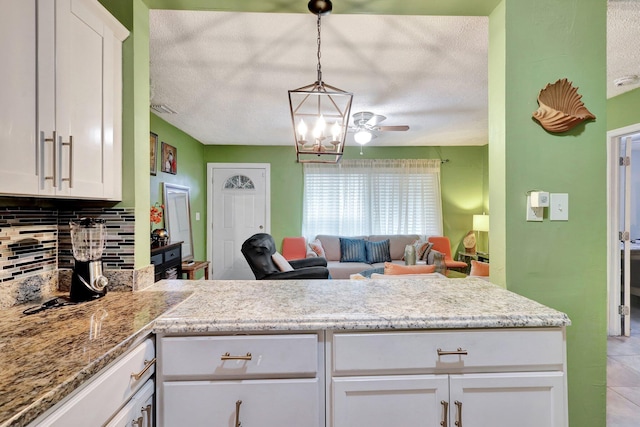 kitchen featuring white cabinetry, ceiling fan, hanging light fixtures, backsplash, and a textured ceiling