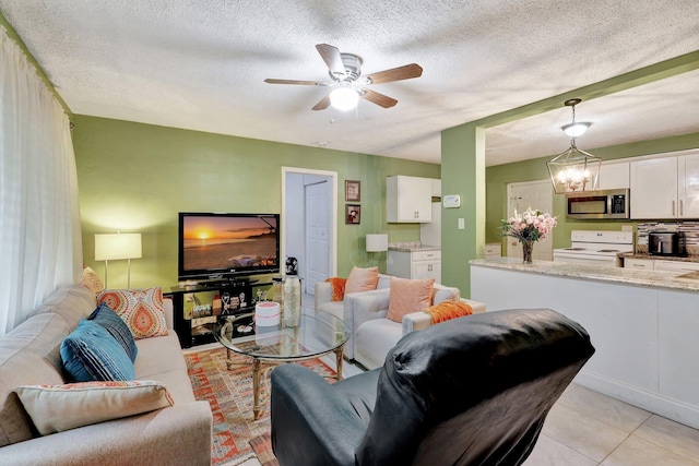 tiled living room featuring ceiling fan with notable chandelier and a textured ceiling