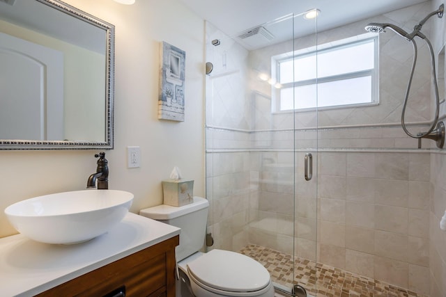 bathroom featuring a shower with door, vanity, and toilet