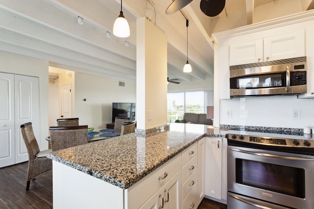 kitchen featuring decorative light fixtures, stove, white cabinetry, and dark stone counters