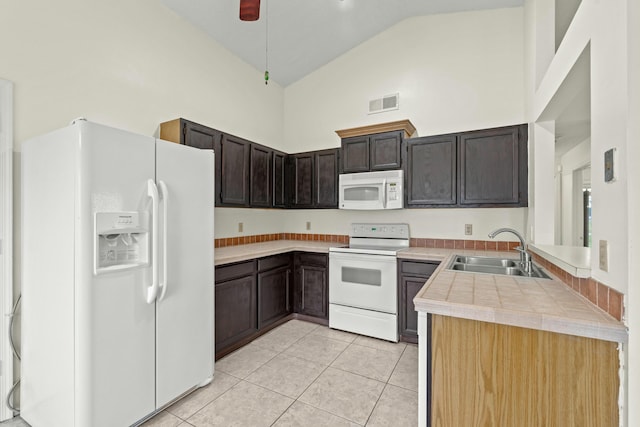 kitchen featuring dark brown cabinetry, sink, high vaulted ceiling, white appliances, and light tile patterned floors