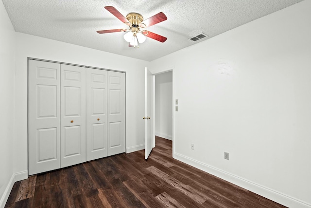 unfurnished bedroom featuring ceiling fan, a closet, dark hardwood / wood-style floors, and a textured ceiling