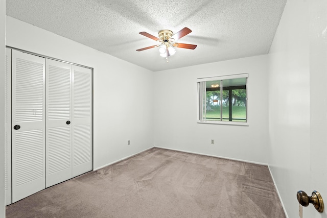 unfurnished bedroom with ceiling fan, light colored carpet, a textured ceiling, and a closet