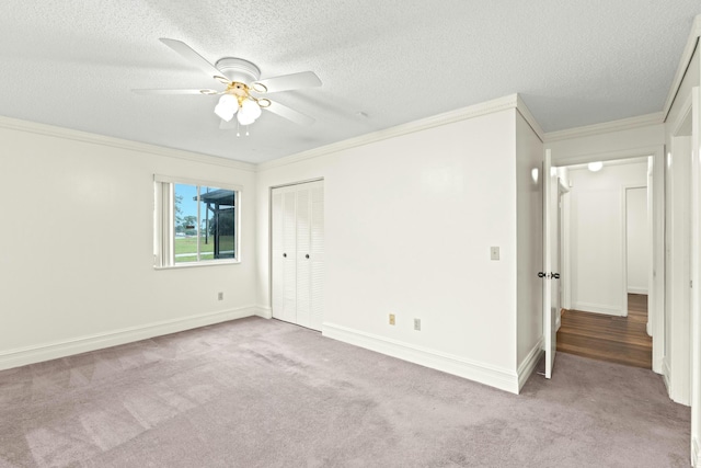 unfurnished bedroom featuring light carpet, a textured ceiling, ceiling fan, and crown molding