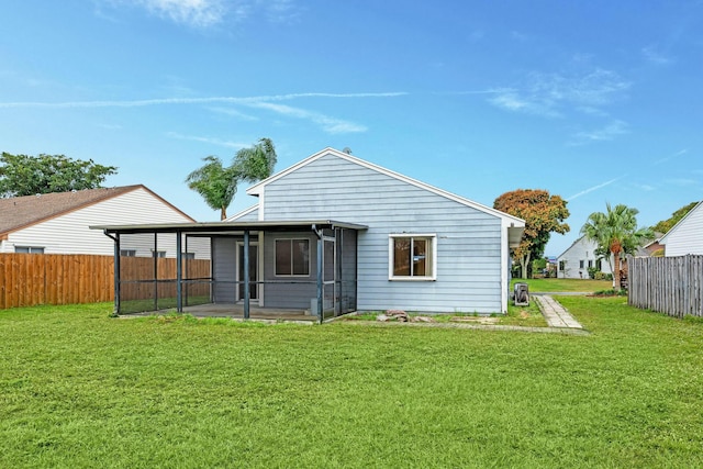 back of house featuring a lawn and a sunroom