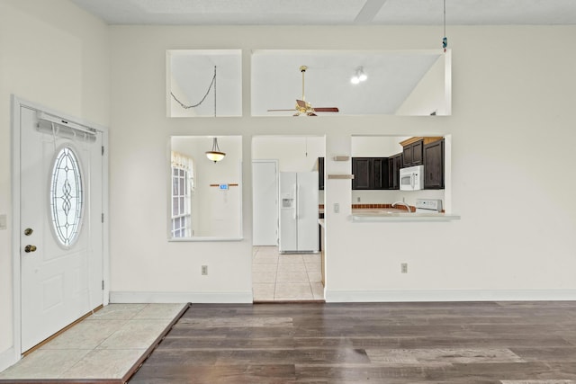 tiled entrance foyer featuring ceiling fan and a towering ceiling